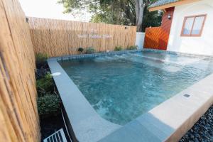 a swimming pool in front of a wooden fence at Tenki poolvilla srisaket in Ban Phia Nam