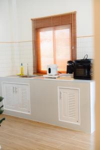 a kitchen with a white counter and a window at Tenki poolvilla srisaket in Ban Phia Nam
