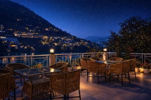 a patio with tables and chairs on a balcony at night at Neelesh Inn - Luxury Lake View Resort with Swimming Pool on Bhimtal Lake in Bhīm Tāl