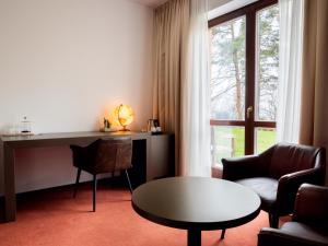 a living room with a table and a desk and a window at Hotel Cvilín in Krnov