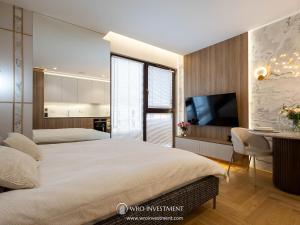 a bedroom with a large bed and a desk and a television at Apartament Studio Sol Marina in Wiślinka