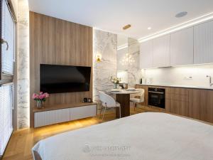 a bedroom with a bed and a kitchen with a tv at Apartament Studio Sol Marina in Wiślinka