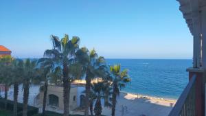 a view of the ocean with palm trees and a building at TRILOCALE DIRETTAMENTE SUL MARE - cod 512 in Porto Recanati