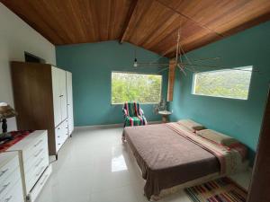 a bedroom with a bed and a blue wall at Casa Morro Branco in Palmeiras