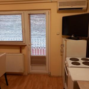 a kitchen with a stove and a refrigerator and two windows at Apartman M 5 in Novi Sad