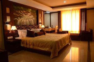 a bedroom with a large bed with a painting on the wall at Hotel Sky Pearl in Kannur