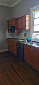 a kitchen with wooden cabinets and a black dishwasher at Himmel Haus in Laguna
