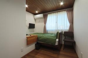 a bedroom with a bed and a desk and a window at ゲストハウスきーず in Nishio +86 photos