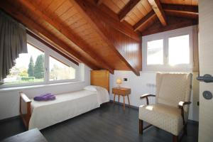a bedroom with a bed and a chair and a window at Holiday Home Lake Orta in Pettenasco