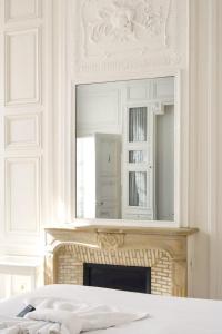 a bedroom with a fireplace with a mirror above it at Suite Luxe · Cour calme · Chartres centre in Chartres