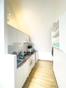 a kitchen with white cabinets and a wooden floor at La Chapelle · Vue cathédrale · Chartres centre in Chartres