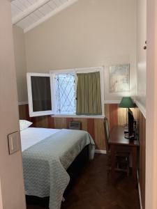 a bedroom with a bed and a desk and a window at Cuatro Soles in Ezeiza