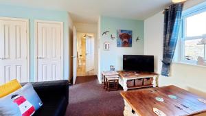 a living room with a couch and a table at Lighthouse Apartment - Part of the The Bay Filey Holiday Village with pool, gym and direct beach access, pub, restaurant, tennis and meadows walks in Filey