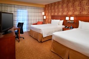 a hotel room with two beds and a flat screen tv at Courtyard Columbus Worthington in Worthington