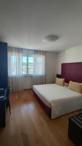 a bedroom with a large bed and a large window at Residence Calissano in Alba