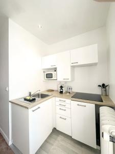 a white kitchen with a sink and a microwave at Les Soeurs · Vue cathédrale · Chartres centre in Chartres