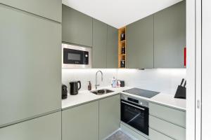 a kitchen with white cabinets and a sink at GuestReady - Menéres Apartments in Matosinhos