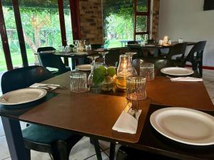 a table with plates and glasses on it in a restaurant at Airport Bird & Game Lodge in Kempton Park