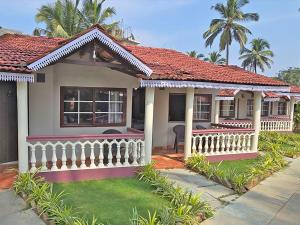 a house with a white fence and palm trees at M Beach Resort in Colva