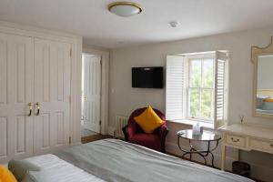 a bedroom with a bed and a chair and a window at The Dixcart Hotel in Sark