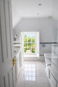 a white bathroom with a window and a tub and a sink at The Dixcart Hotel in Sark +39 photos