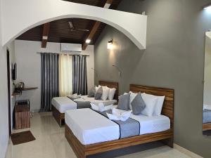 two beds in a hotel room with an arch at M Beach Resort in Colva