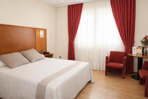 a hotel room with a bed and a red chair at Motel Punta Cana in Santiago de Compostela