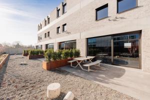 a building with a table and benches in front of it at Coliving - Bord de Meuse - L'échappée Mosane in Oupeye