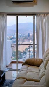 a living room with a couch and a large window at Monochrome County 16th floor in Dehu Road