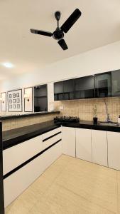 a kitchen with white cabinets and a ceiling fan at Monochrome County 16th floor in Dehu Road