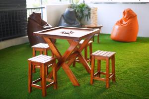a table with four stools and a table with a game at Veedu and Co Greens in Cochin