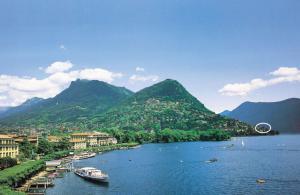 a group of boats on a river with mountains at Barony Olive mit Hund in Lugano +22 photos