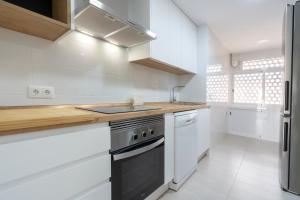 a kitchen with white cabinets and a stove top oven at Playa Anaconda - Wellhome Alicante in Benimagrell