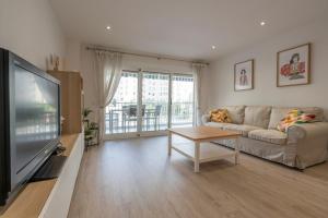 a living room with a couch and a tv at Playa Anaconda - Wellhome Alicante in Benimagrell