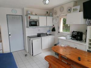a kitchen with white cabinets and a wooden table at Le VALLON à POR-NIC in Pornic