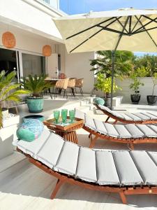 a patio with white chairs and an umbrella at Villa TerraAurora in Barbat na Rabu