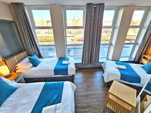 a hotel room with three beds and large windows at Abigail's Hostel in Dublin