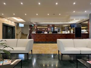 a lobby with two white chairs and a counter at As Hotel Dei Giovi in Cesano Maderno
