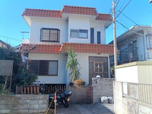 a house with a motorcycle parked in front of it at YCS2 Guest house, good access to Shinjuku in Nishitokyo