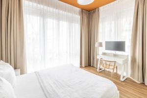 a bedroom with a bed and a desk with a television at Midi Inn Parkhotel Mitte in Berlin