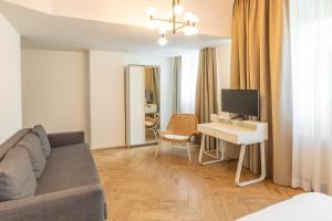 a living room with a couch and a desk with a television at Midi Inn Parkhotel Mitte in Berlin