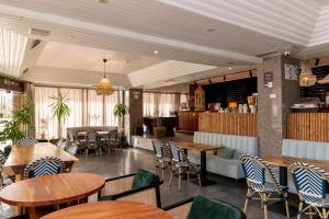a restaurant with wooden tables and chairs and a bar at WOT Costa da Caparica Soul in Costa da Caparica
