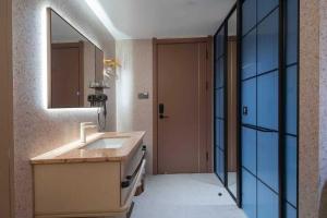 a bathroom with a sink and a mirror and a door at Zhuoya Garden Hotel in Beijing