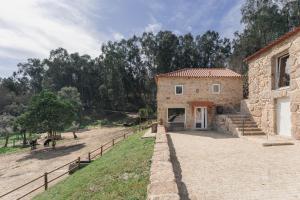 a stone building with a fence next to a yard at Banduja Reserve - Slow by nature in Celorico de Basto
