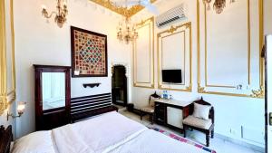 a bedroom with a bed and a desk and a television at Lake Pichola Hotel in Udaipur