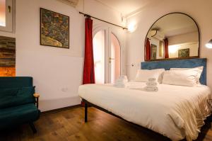 a bedroom with a large bed and a green chair at Medieval central apartment in Bologna