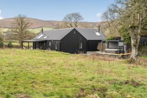 a black house sitting on a hill in a field at Grove Cottage in Kington