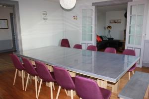 a dining table with purple chairs in a room at Gîte with pool & Nordic bath in Monthois +56 photos
