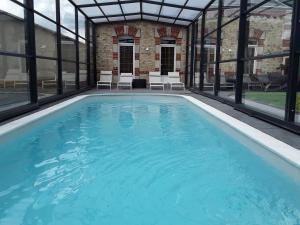 a large swimming pool with windows and a building at Gîte with pool & Nordic bath in Monthois