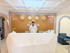 a man standing behind the counter of a restaurant at The 7 elevan hotel in Sānand